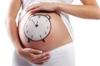 Illustration for a blog post about determining the due date – a pregnant woman’s belly with a painted clock on it.