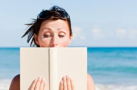 Illustration for a blog post about the outdated rhythm method – the surprised face of a woman reading a book on the beach.